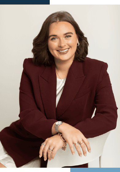 Smiling woman in burgundy blazer, seated.